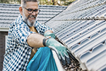 man cleaning home gutters