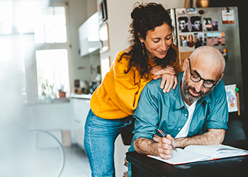 woman looking over man's shoulder at paperwork