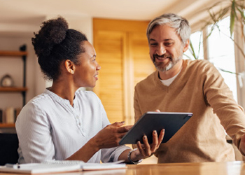 man and woman laughing and looking at tablet