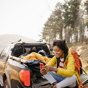 Young woman sitting on bed of truck