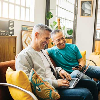 two men sitting on couch on laptop