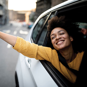 woman smiling out window of car