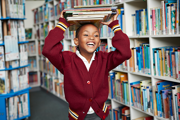 young student balancing books on head